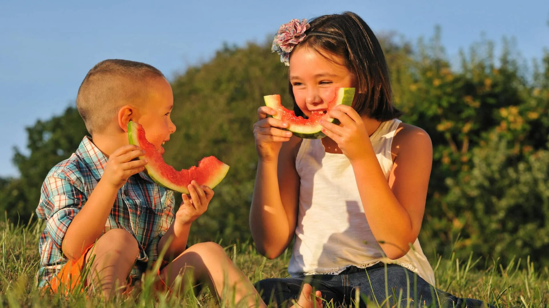 Children enjoying watermelon outdoors.