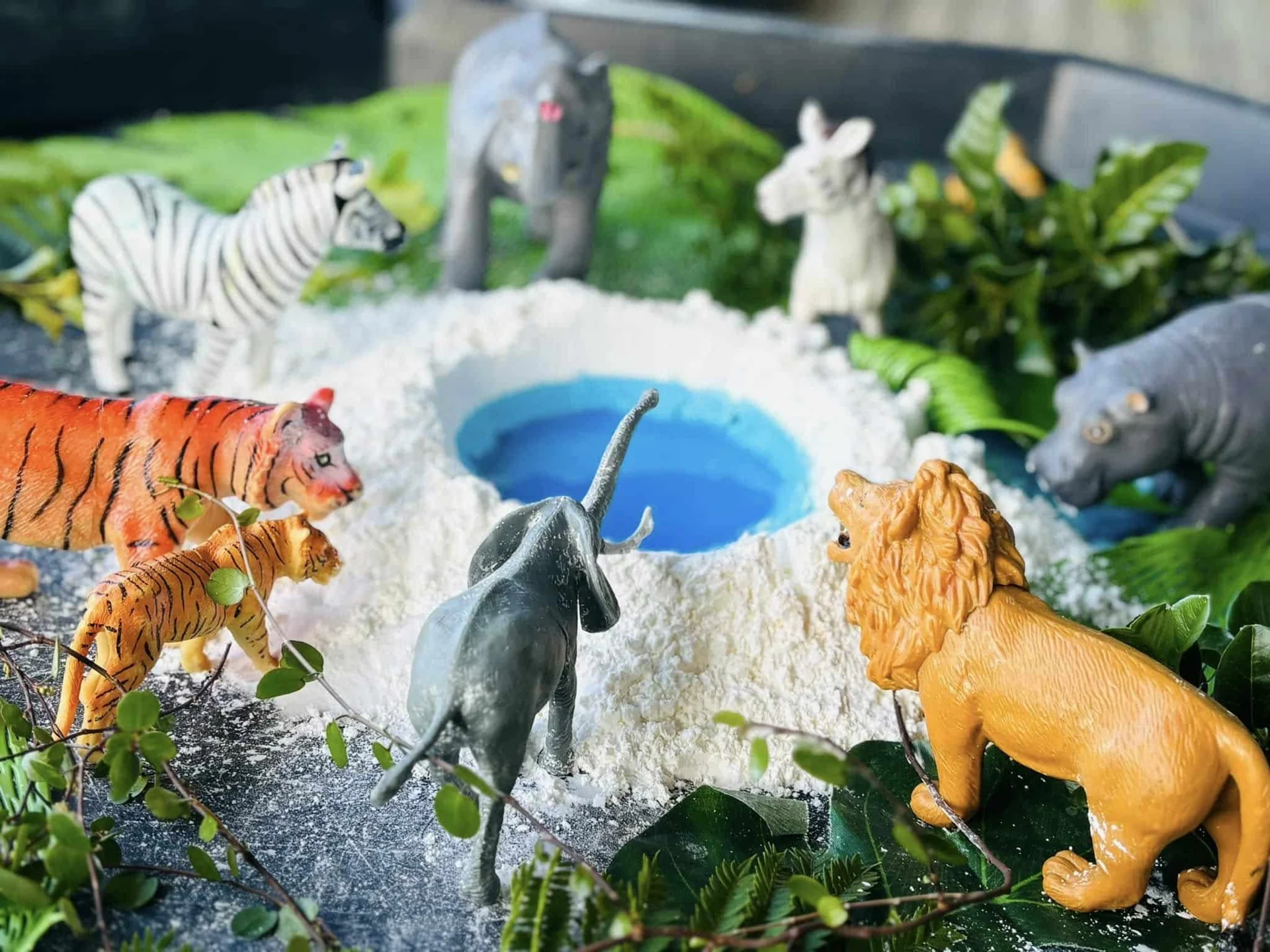 Toy animals around a blue pond