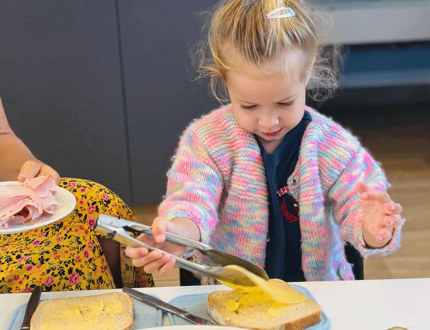 Child preparing sandwich with mustard.