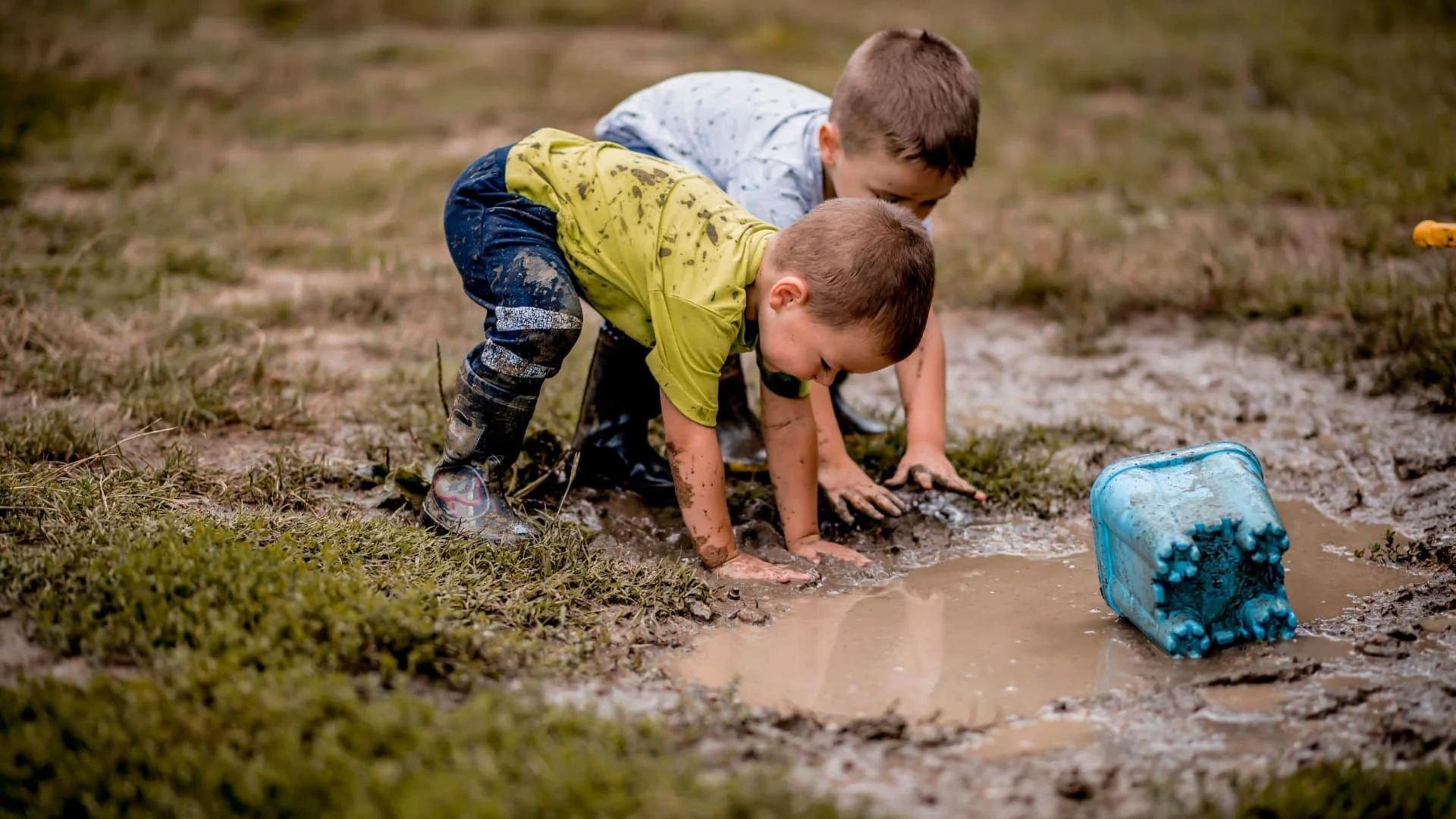 Two children playing in muddy puddle